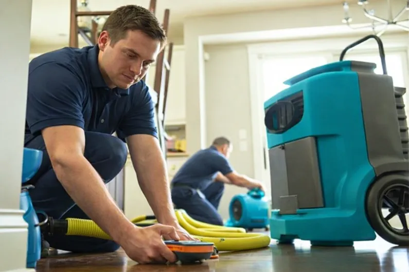 Workers using professional water damage extraction equipment.